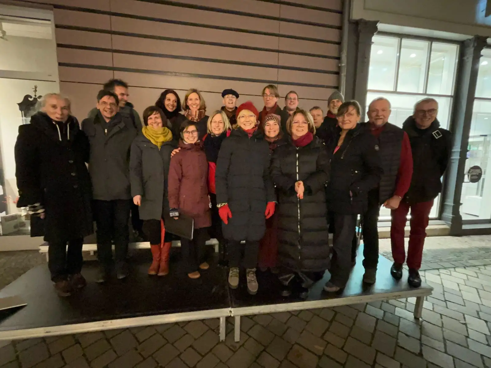 Der Jazzchor inTune posiert draußen im Dunkeln auf einer kleinen Bühne für ein Gruppenfoto.